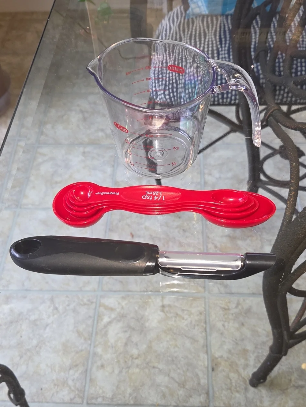 Clear Glass Measuring Pitcher with Red Nesting Measuring Spoons and Black Peeler